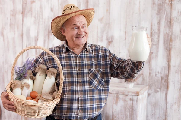 Hombre experimentado agricultor senior con productos lácteos — Foto de Stock