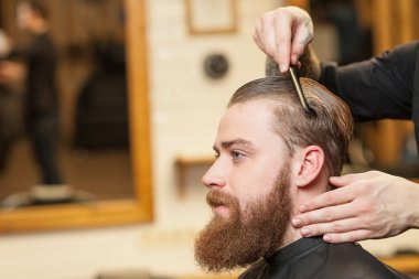 Cheerful male barber is serving his client