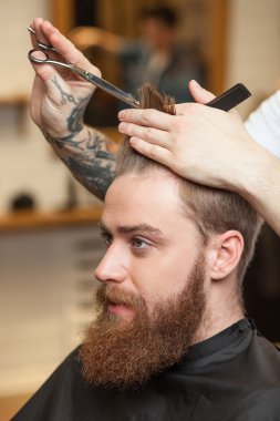 Cheerful bearded guy is attending the hairdresser