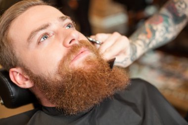 Cheerful bearded hipster is attending hair salon