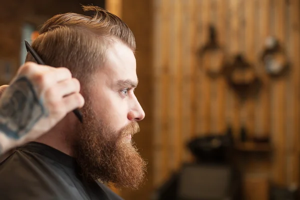 Professional young barber with a comb at beauty shop — Stock Fotó