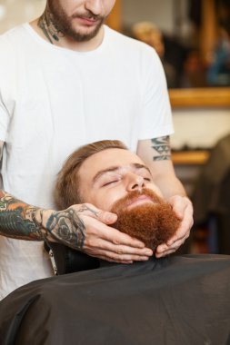 Cheerful male barber is serving his customer
