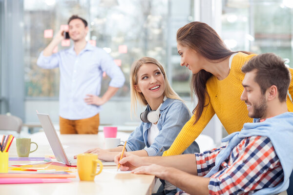 Cheerful young colleagues are discussing new project
