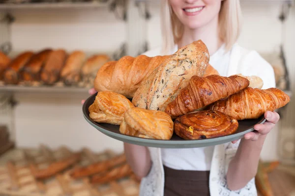 Cheerful female baker is proposing fresh bread — Stock fotografie