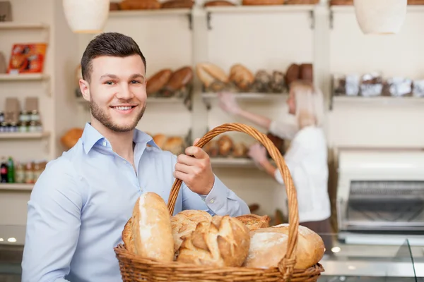 Attractive young guy is purchasing fresh bread — Stock fotografie