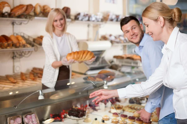 Cheerful young saleswoman is selling fresh bread — Stock fotografie