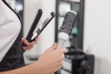 Cheerful female hairstylist is working in beauty salon