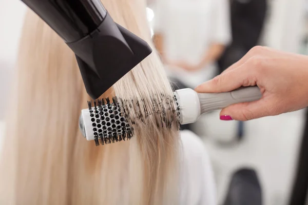 Professional female hairstylist is working with hair-drier — Zdjęcie stockowe