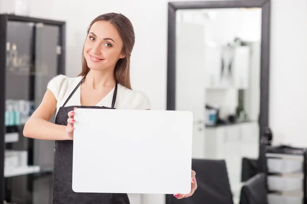Cheerful female hairdresser is showing a placard — Stock Photo, Image