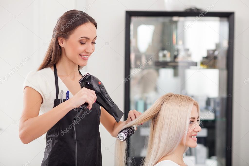 Attractive female hairstylist is working with joy