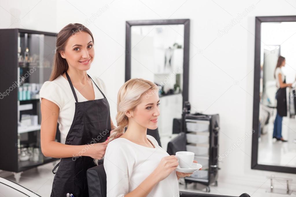 Beautiful blond girl is getting hairstyle by hairdresser