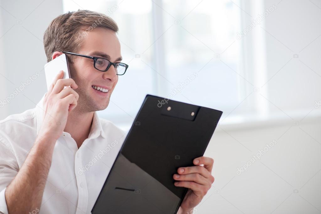 Handsome young businessman is communicating on telephone
