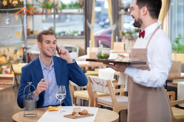 Attractive male cafe worker is serving the customer — Stockfoto