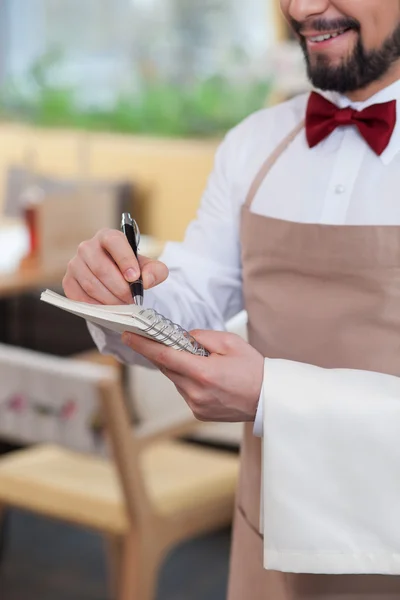 Pretty young waiter is receiving an order — Stockfoto