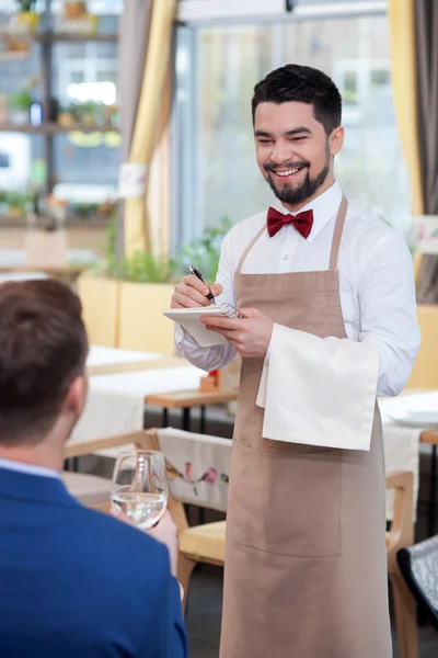 Alegre joven camarero está sirviendo a un cliente — Foto de Stock