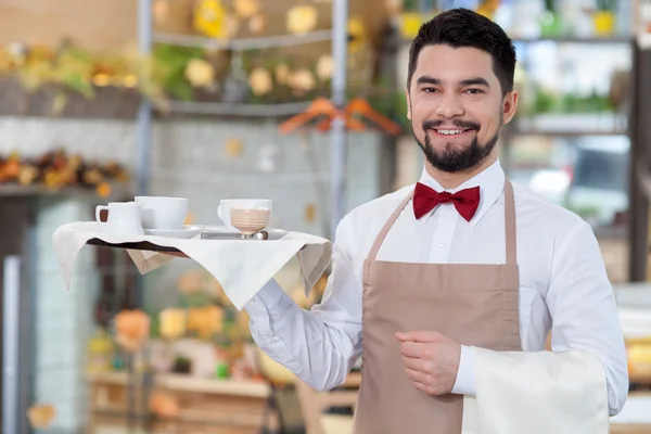 Handsome male cafe worker is serving a customer — Stock fotografie