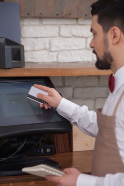 Attractive male cafe worker is receiving payment