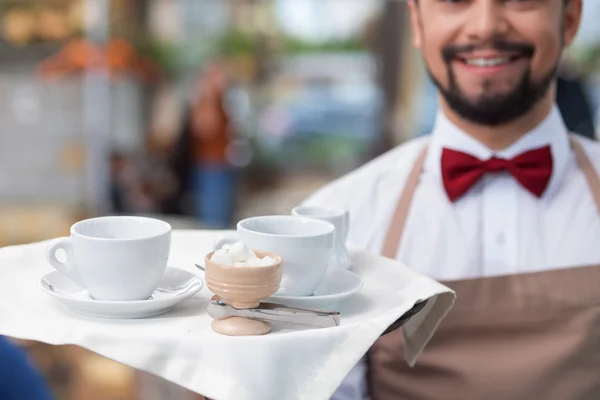 Bonito trabalhador café masculino está servindo um cliente — Fotografia de Stock