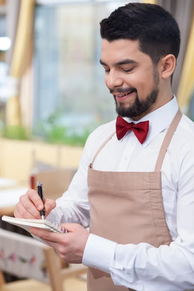 Attractive young waiter is receiving an order — Stockfoto