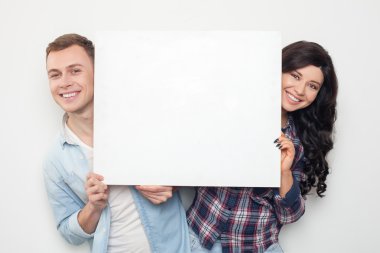 Attractive man and woman are advertising a placard