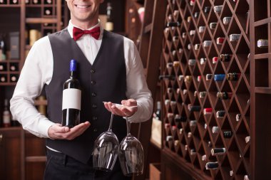 Skillful young sommelier is serving a customer
