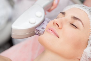 Skillful young cosmetologist is treating female face
