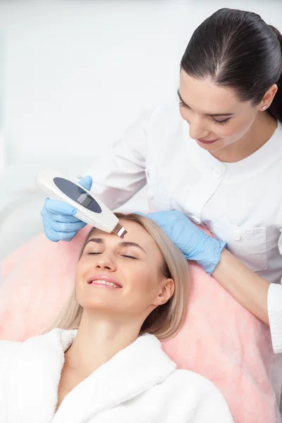 Jovem cosmetologista alegre está passando por tratamento de cavitação — Fotografia de Stock