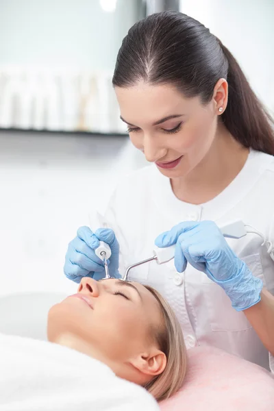 Attractive young beautician is treating her patient — 스톡 사진