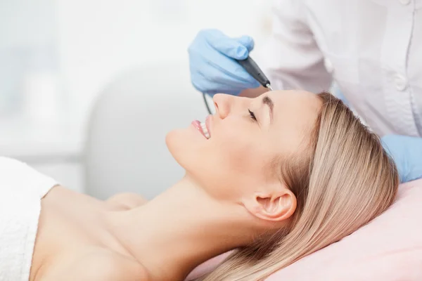Skillful young cosmetologist is treating her patient