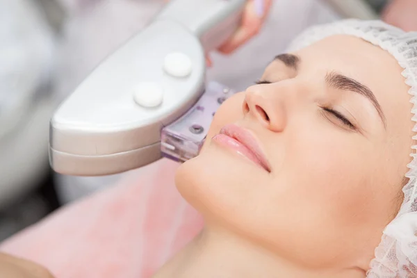 Skillful young cosmetologist is treating female face