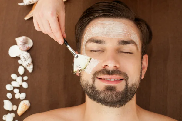 Cheerful young guy is getting skin treatment