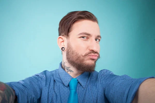 Cheerful bearded young guy is photographing himself — Stockfoto