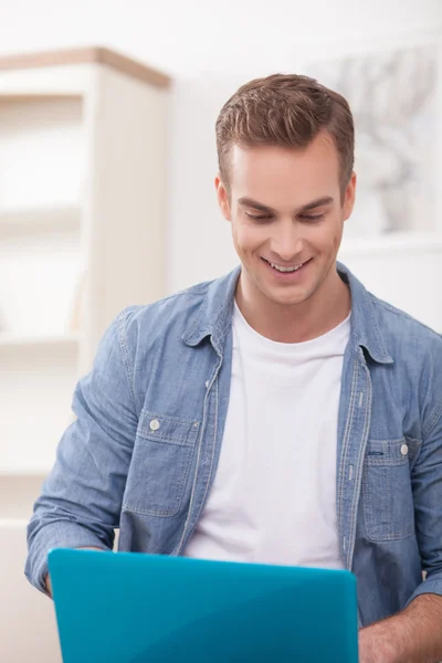 Cheerful guy is using a notebook at home — Stock Fotó