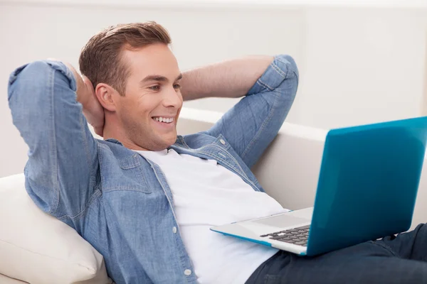 Handsome young man is using a laptop — Stock Fotó