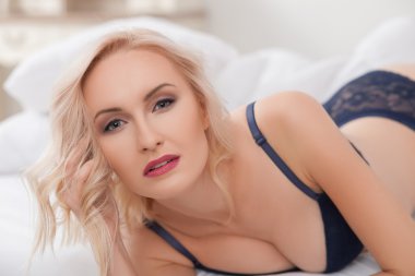 Attractive young woman is luxuriating in bedroom