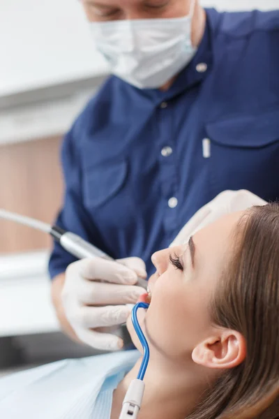 Atractivo joven médico dental está curando a su paciente — Foto de Stock