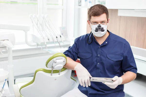 Odontólogo guapo está trabajando con equipos modernos — Foto de Stock