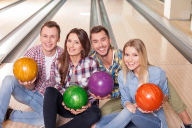 Cheerful young friends are playing kegling together