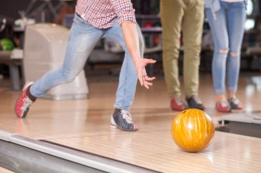 Cheerful young fit guy is playing kegling
