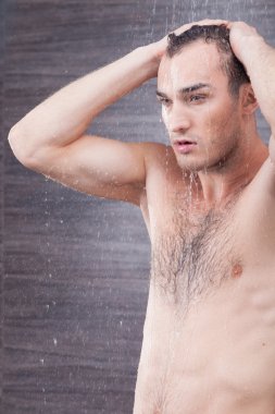 Handsome young guy is washing his body