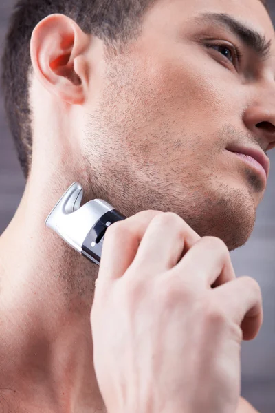 Handsome young guy with special shaver — Stockfoto