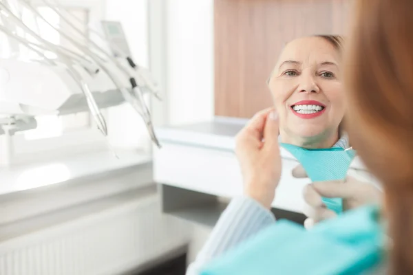 Cheerful mature lady is checking work of orthodontist — Stock fotografie