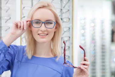 Attractive young woman is wearing spectacles in shop