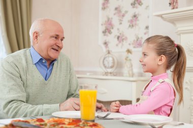 Cute small girl is dining with her grandparent