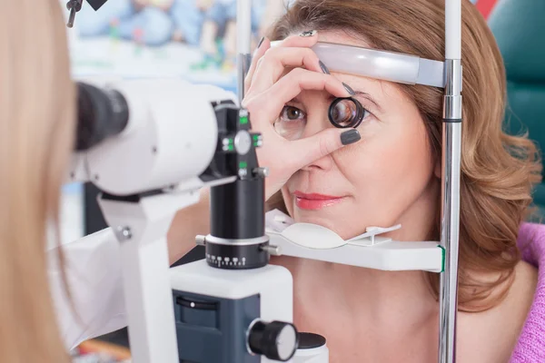 Oftalmologista profissional feminino está verificando os olhos humanos — Fotografia de Stock