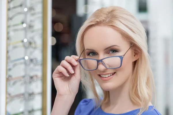 Pretty young woman is choosing new glasses — Stok fotoğraf