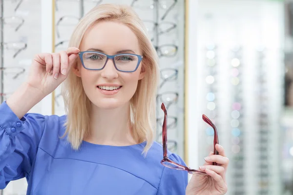 Attractive young woman is wearing spectacles in shop — Stock fotografie