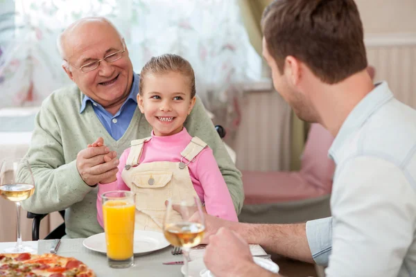 Cheerful mature grandfather is dining with his children — Zdjęcie stockowe