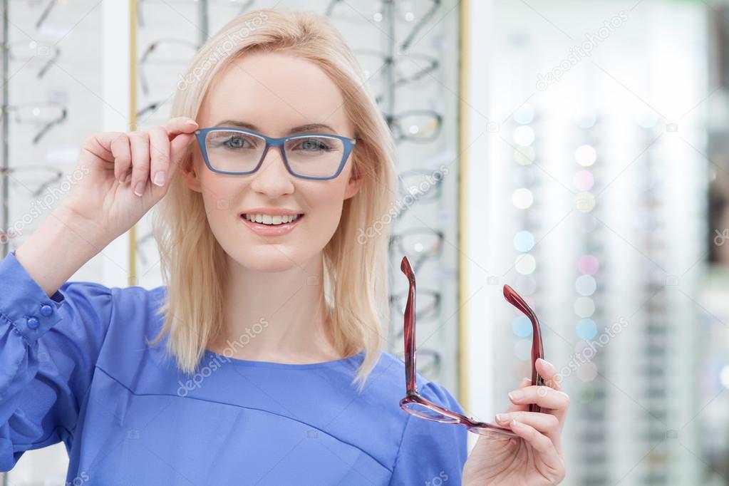 Attractive young woman is wearing spectacles in shop