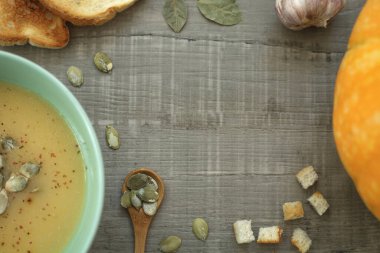 Gri arka planda çekirdekli balkabağı kremalı çorba. Üst görünüm, alanı kopyala